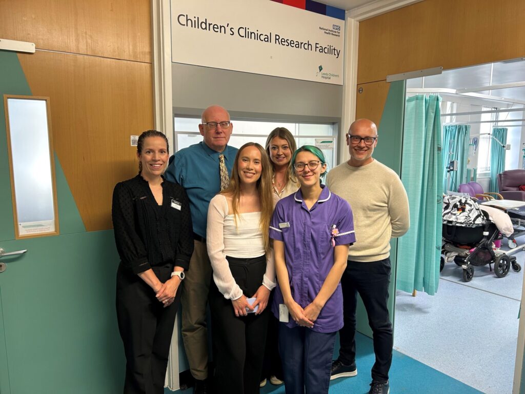 An image of the visitors under a sign for the Children's Clinical Research Facility.